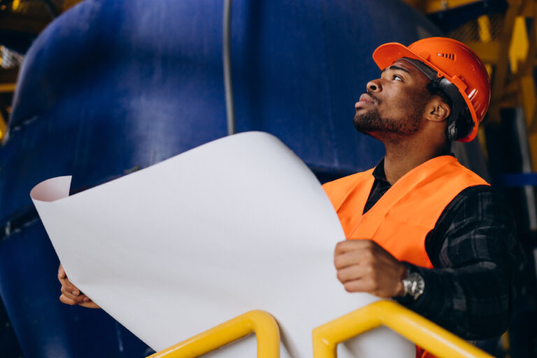 African american worker standing in uniform wearing a safety hat in a factory